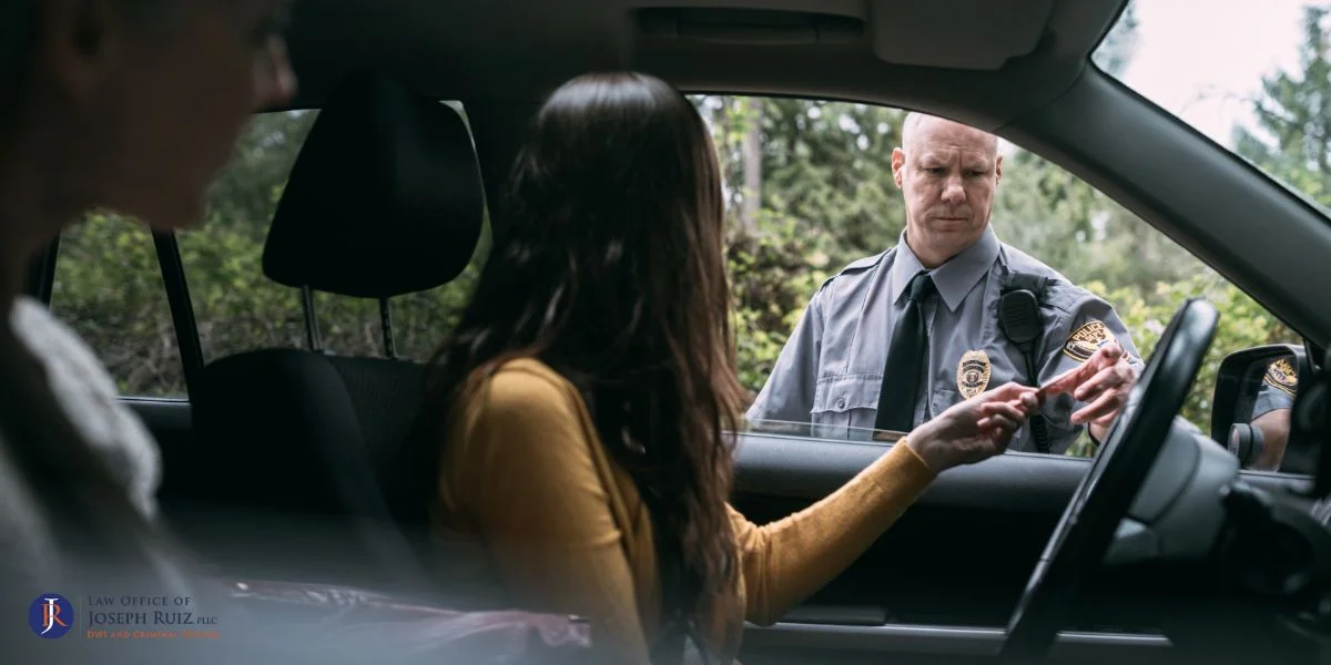 Woman in a car handing a document to a police officer, illustrating a DWI traffic stop, relevant to DUI plea bargain implications in Texas.